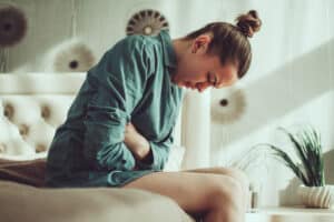 Woman sitting on edge of bed, distressed due to overactive bladder