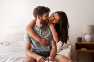 Man and woman smiling at each other on the bed after vasectomy in Hartford, CT