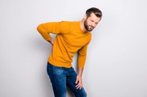 Man holding his lower back, grimacing in pain due to kidney stones in Hartford, CT
